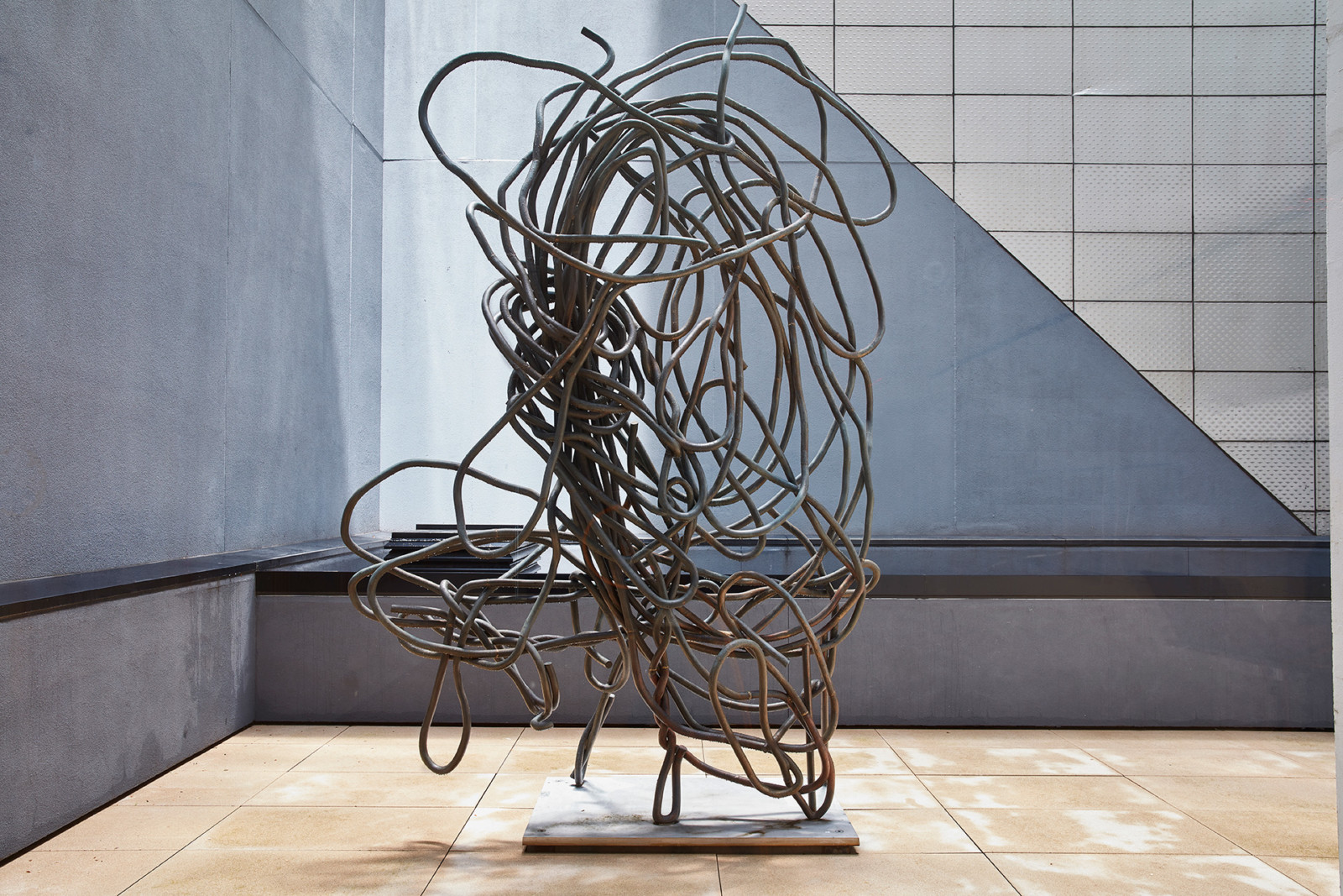 An abstract sculpture with a rectangular base positioned centrally in an outdoor terrace