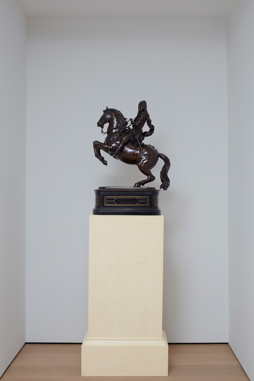 View of a bronze equestrian statue one a pedestal inside a white-walled niche