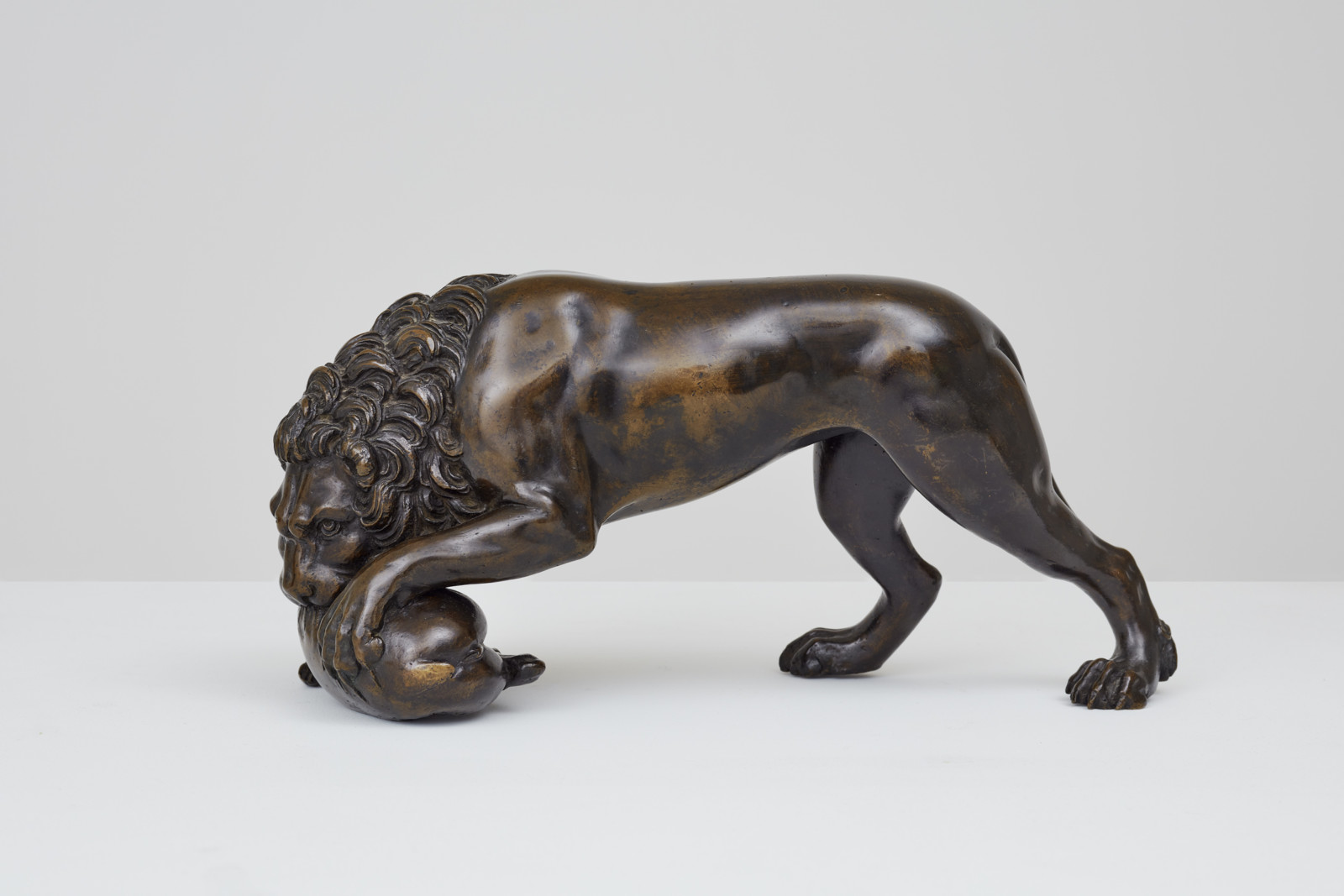 Statuette of a lion with its mouth clenching down on a doe's body
