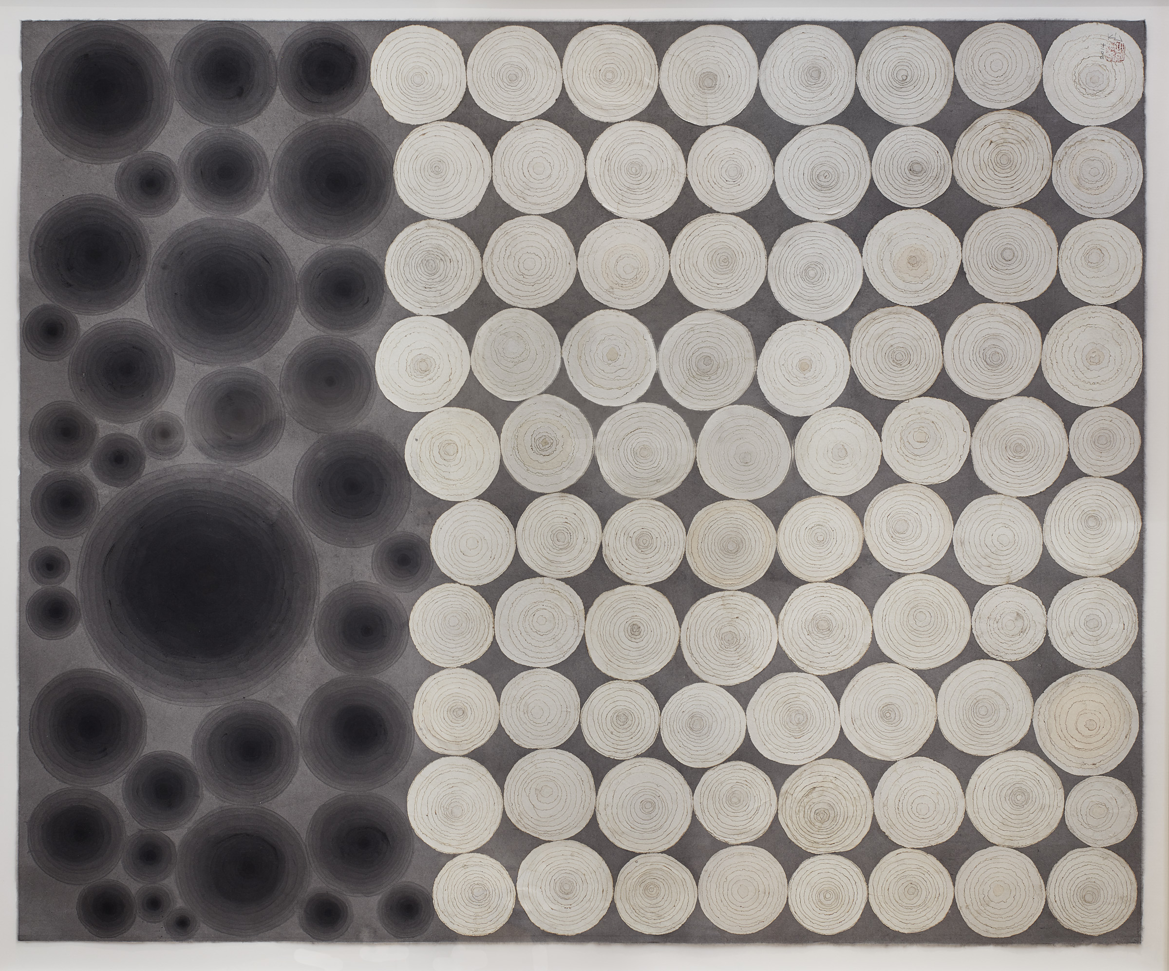 Grey canvas two-thirds covered with overlaid white circles and the other third painted with repeated black ink circles.