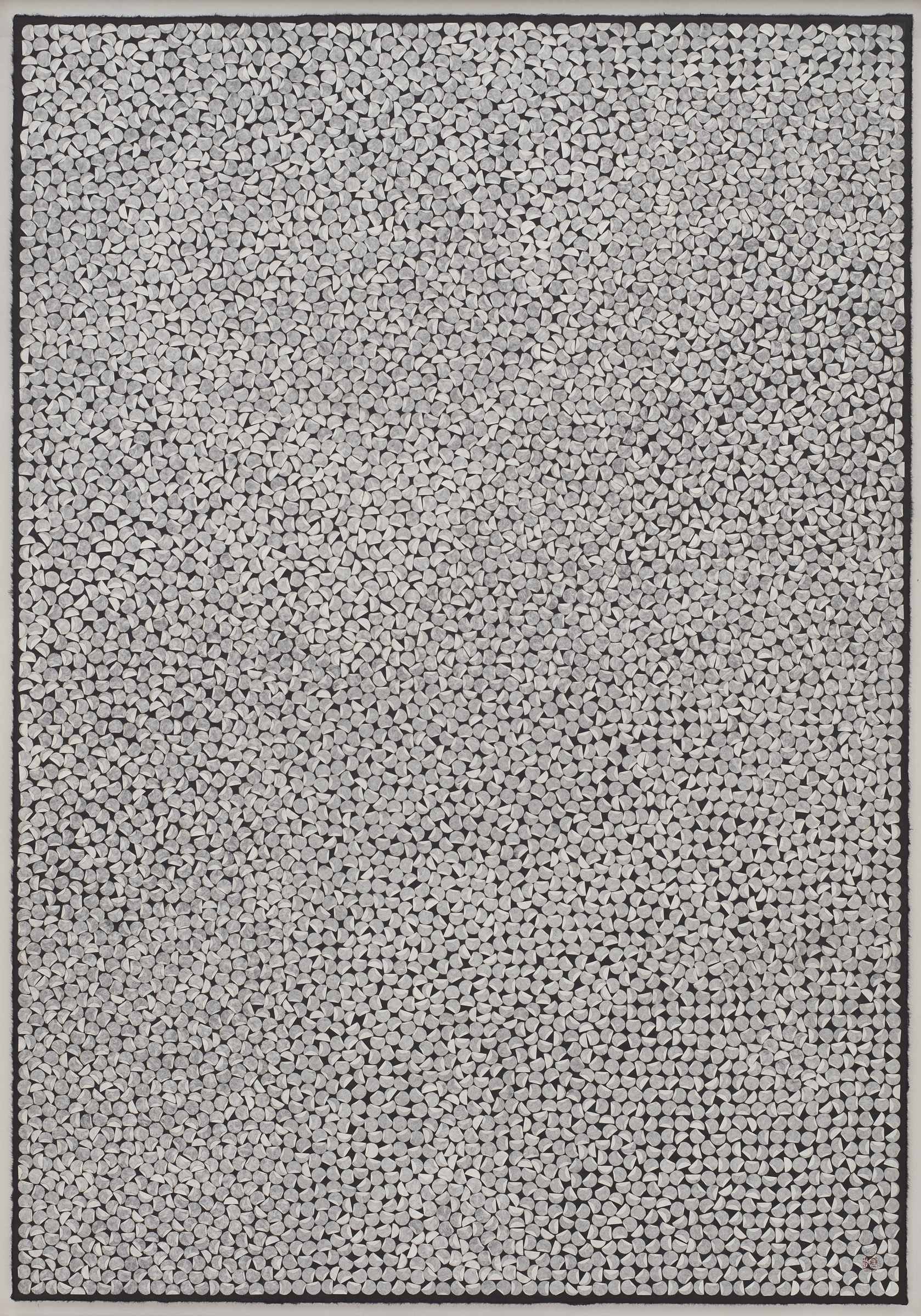 Tiny cut out, circular pieces of paper covering a black canvas.
