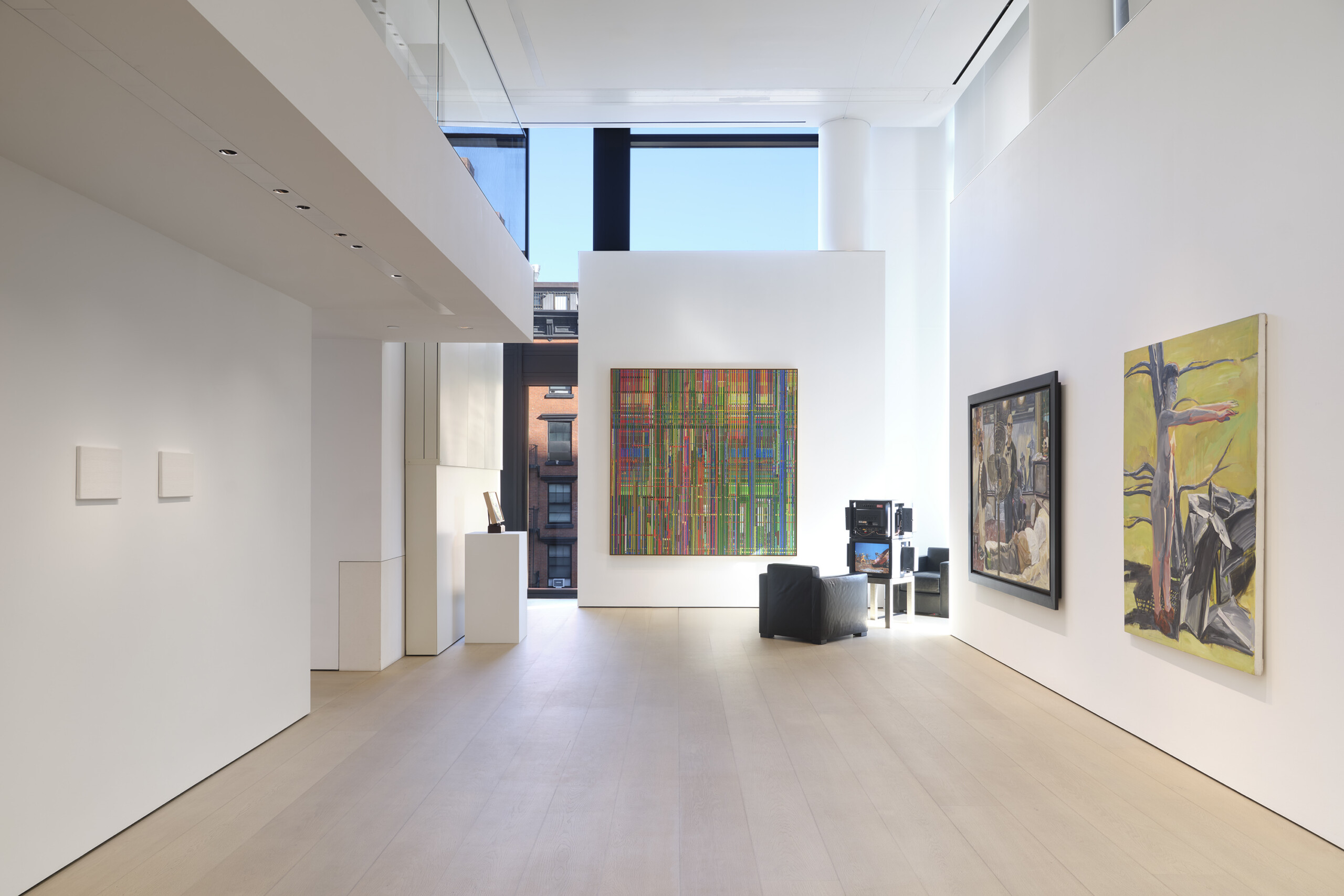 a gallery view, at the end of the gallery there are several TVs, a green and red painting